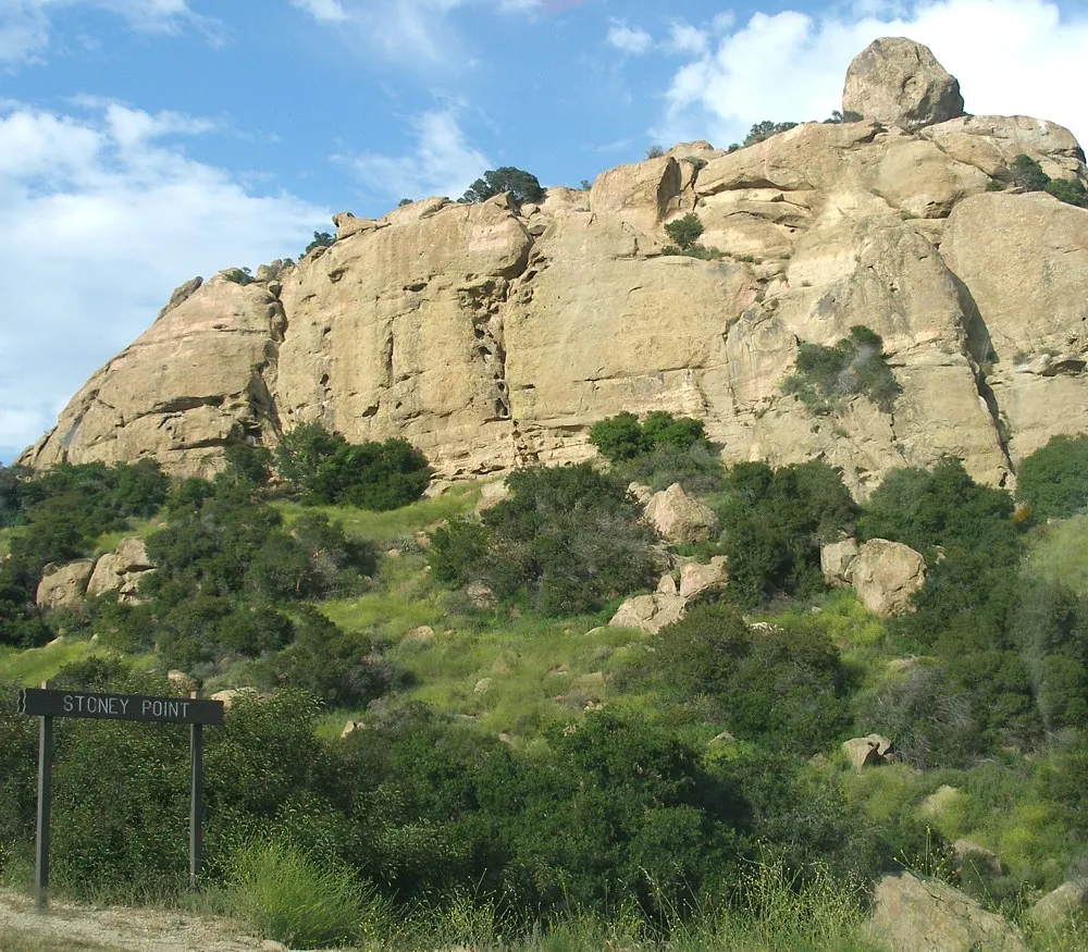 The main sandstone formation at Stoney Point rising above green brush under a blue sky