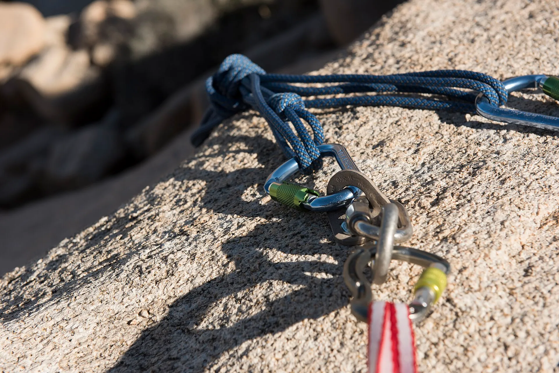 Close-up of a blue rope running through locking carabiners on a chain anchor